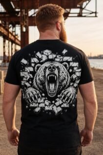Mann von hinten trägt ein schwarzes T-Shirt mit großem Rückenprint eines brüllenden Bären am Hafen bei Sonnenuntergang.