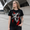 Frau mit schwarzem T-Shirt und großem heulendem Wolf-Motiv in Weiß und Rot, steht vor moderner Betonarchitektur.
