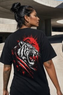 Schwarzes T-Shirt mit brüllendem Tiger-Backprint in Rot und Weiß, getragen von einer Person von hinten in urbaner Architektur.