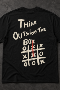Schwarzes T-Shirt liegend auf grauem Untergrund, das Motiv „Think Outside the Box“ in Beige und Rot sowie ein kleines Karabinerelement unten rechts.