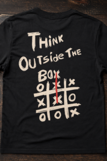 Ausgebreitetes schwarzes T-Shirt auf dunkler Holzoberfläche, vorne mit hellem „Think Outside the Box“-Print und Tic-Tac-Toe-Grafik mit rotem Strich.