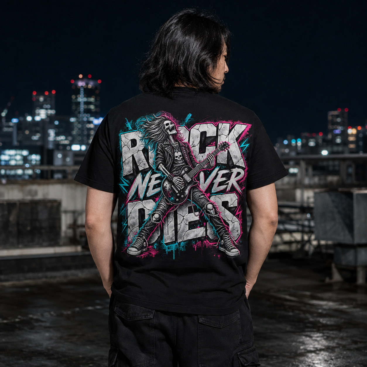 Rothaarige Frau von hinten trägt schwarzes Rock T-Shirt mit großem „Rock Never Dies“-Motiv vor einer Graffiti-Wand, concert outfit im Alternative-Look