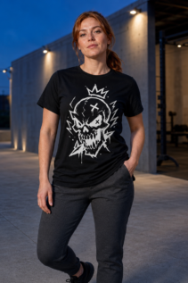 Frau trägt ein schwarzes T-Shirt mit weißem Totenkopf-Motiv als Lifestyle-Aufnahme im Abendlicht vor moderner Architektur; dark streetwear, gothic tshirt.
