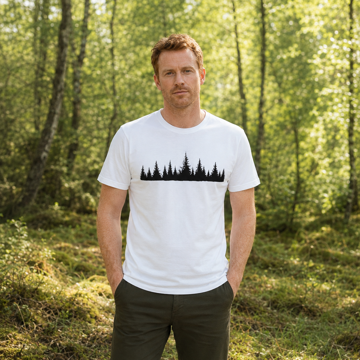 Mann steht im Wald und trägt ein weißes T-Shirt mit schwarzer Wald-Silhouette auf der Vorderseite.