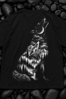 Schwarzes Wolf T-Shirt flach auf dunklen Steinen präsentiert, mit zentriertem schwarz-weißem Wolfmotiv und Mond über dem Wald.