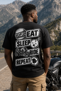 Mann von hinten trägt ein schwarzes Eat Sleep Ride T-Shirt an einer Bergstraße neben einem Motorrad, sportlicher Motortad-Fan-Look