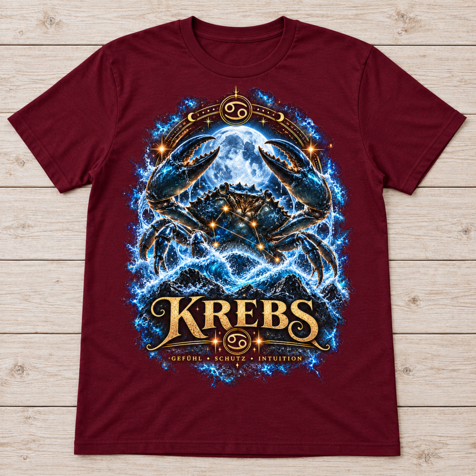 Flach liegendes bordeauxfarbenes T-Shirt mit Krebs-Motiv auf hellem Holzuntergrund, keine Person sichtbar.