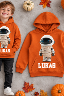 Personalisierter orangefarbener Hoodie mit Mumien-Astronaut-Motiv und Name Lukas, neben einem getragenen Kinderoutfit auf neutralem Hintergrund.